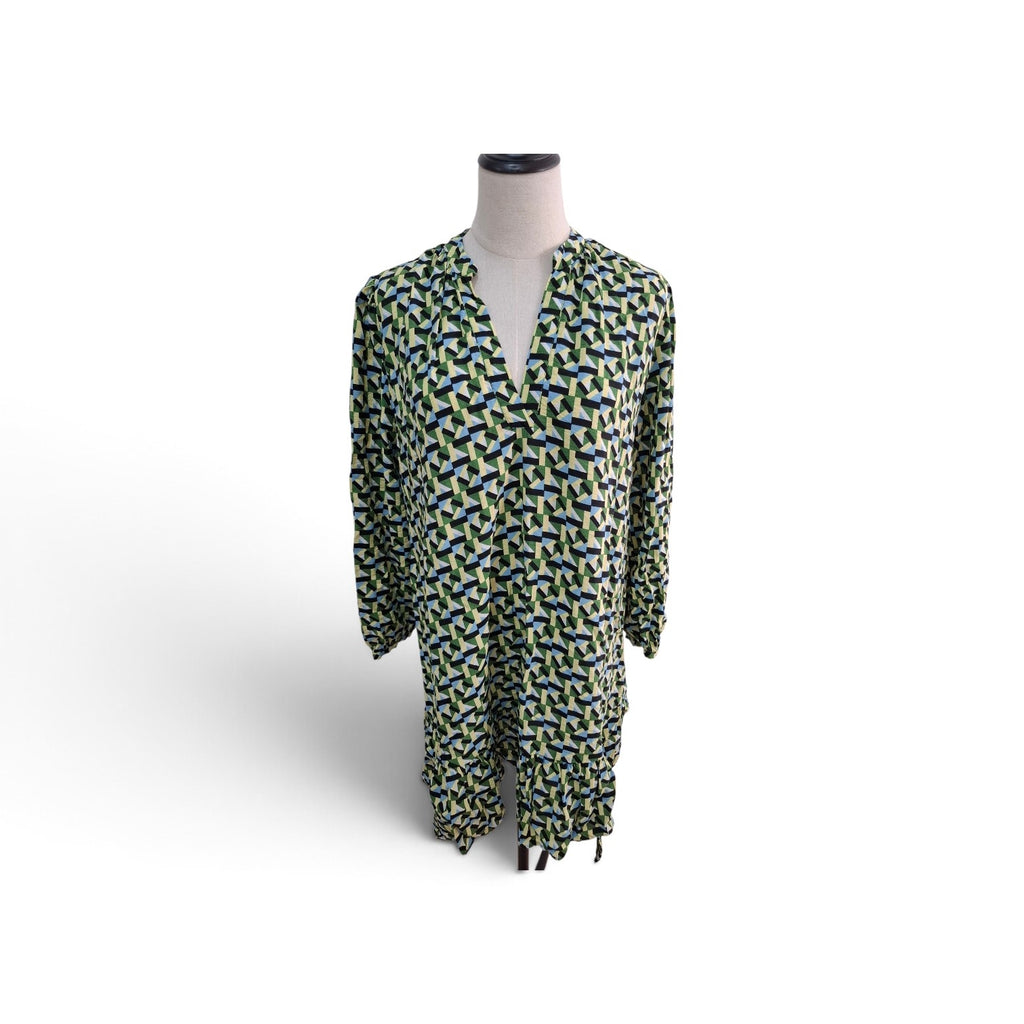 A long-sleeve V-neck tunic dress with an all-over abstract geometric pattern in green, blue, and yellow on a white base, displayed on a mannequin torso against a white background.