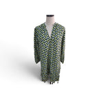 A long-sleeve V-neck tunic dress with an all-over abstract geometric pattern in green, blue, and yellow on a white base, displayed on a mannequin torso against a white background.