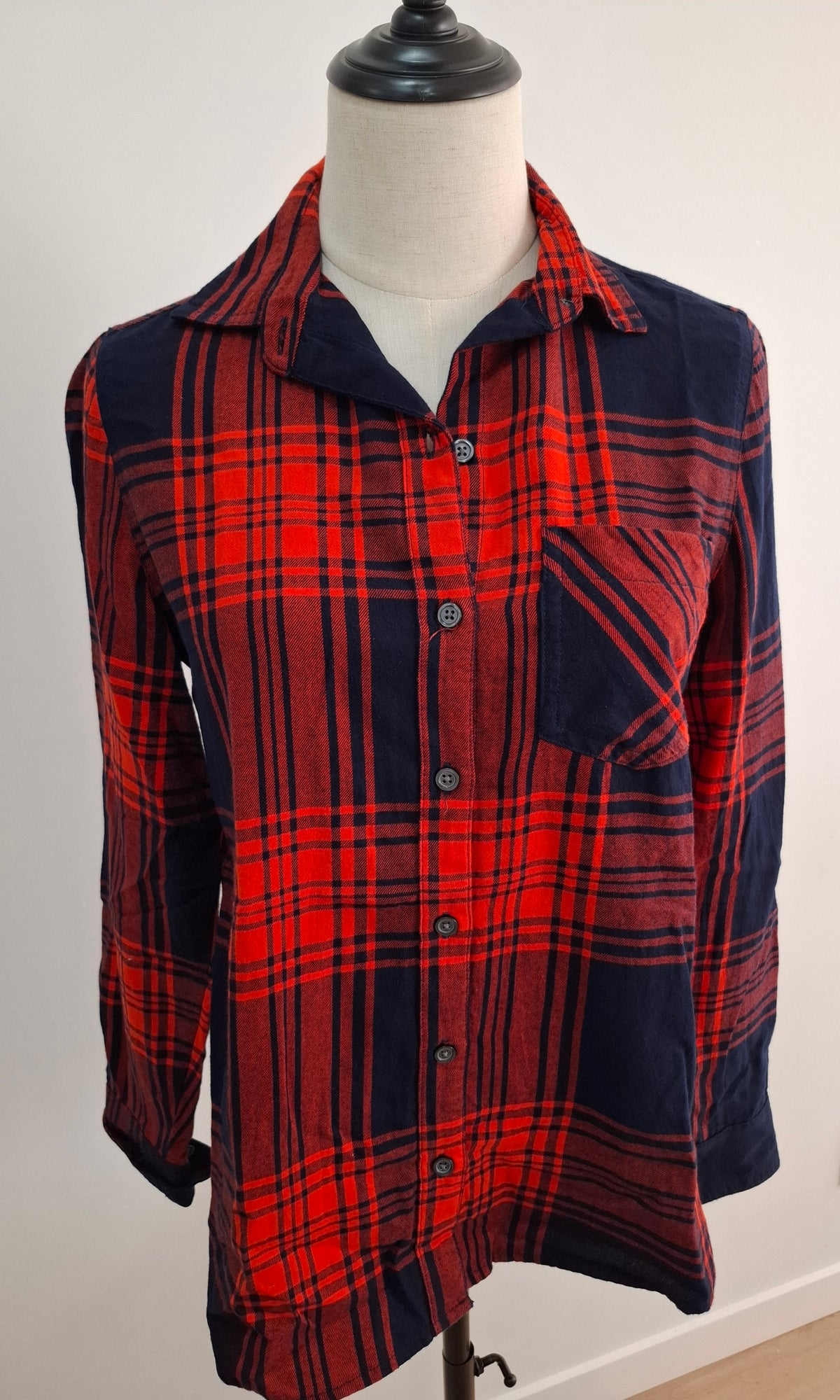 A red and navy blue plaid button-up flannel shirt displayed on a mannequin torso.