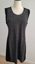 A sleeveless black and gray herringbone knit dress displayed on a mannequin torso against a plain light gray wall.