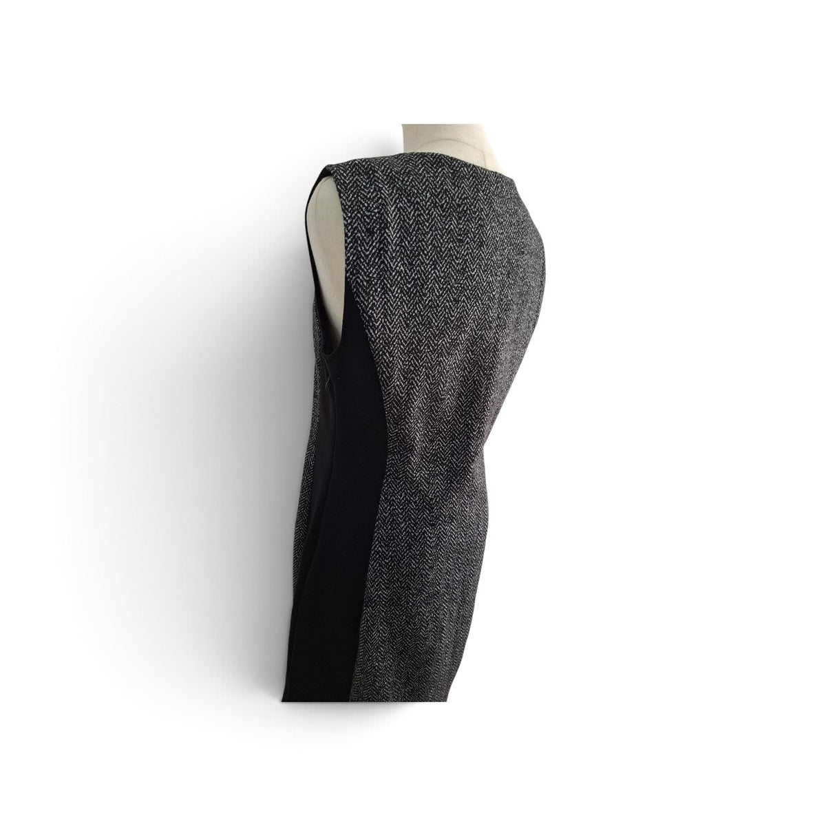 A sleeveless black and gray herringbone tweed vest displayed on a mannequin torso against a plain white background.