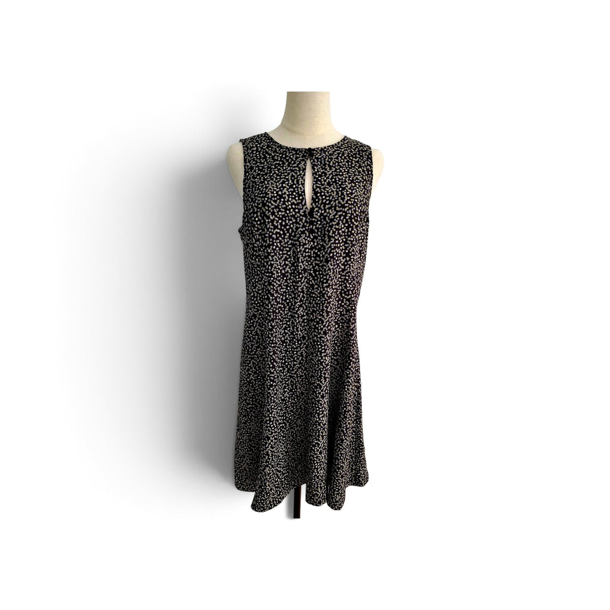 A sleeveless black dress with a small beige leopard print pattern, displayed on a mannequin torso against a white background.