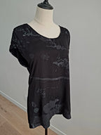 A black short-sleeve top with a gray distressed or faded abstract pattern, displayed on a cream dress form mannequin.