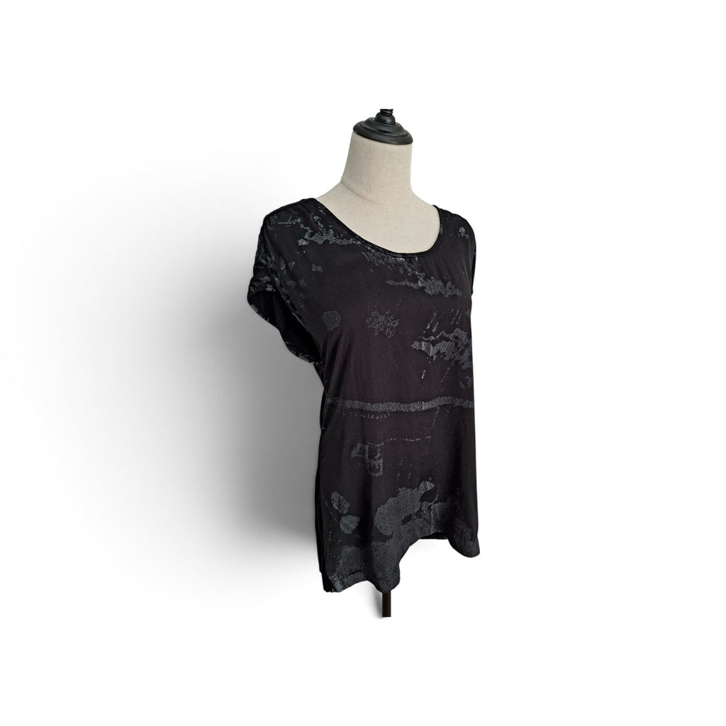 A black short-sleeve top with a distressed, tonal abstract pattern, displayed on a mannequin torso against a white background.