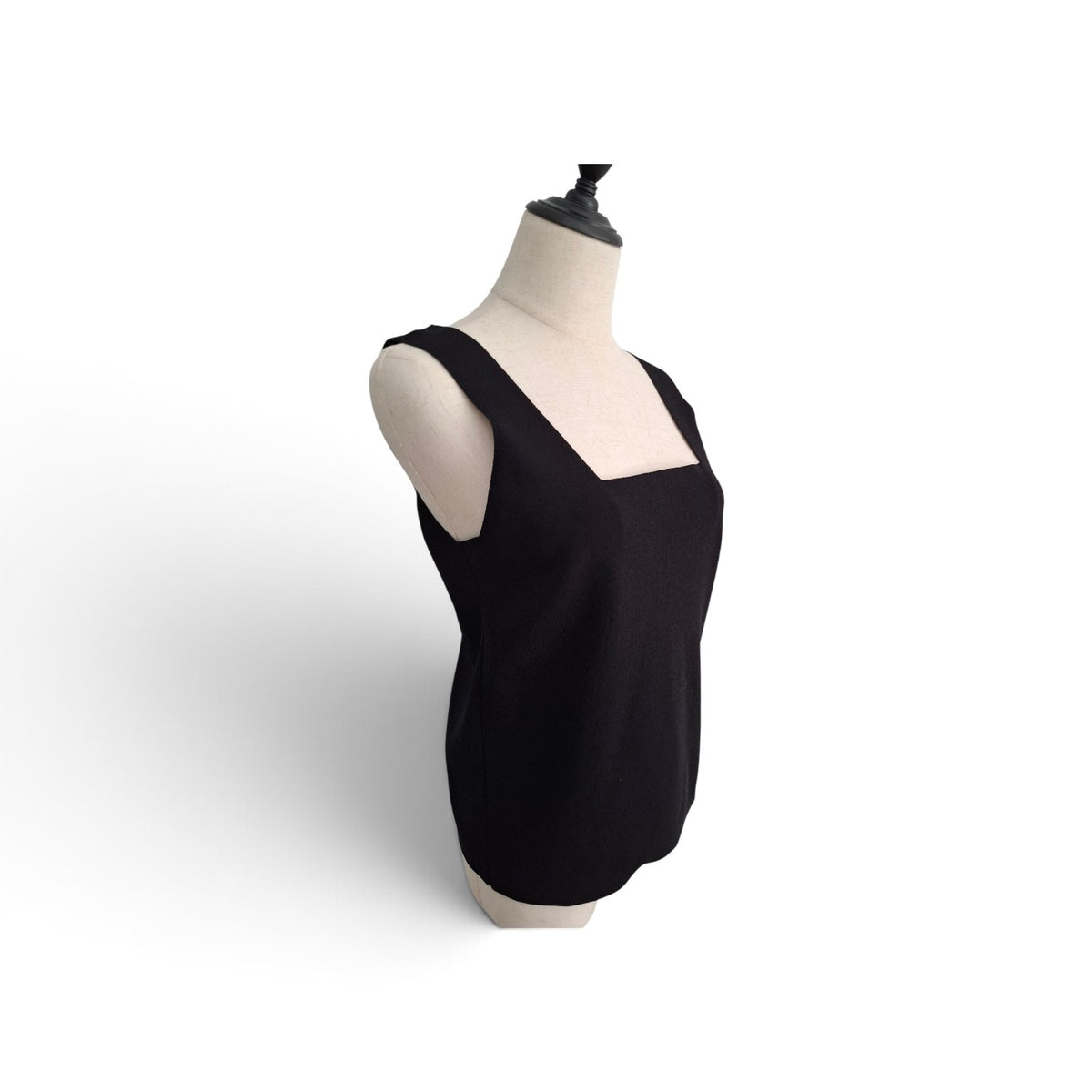 A black sleeveless knit top with a square neckline, displayed on a cream-colored dress form mannequin against a white background.