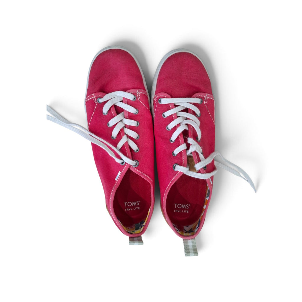 A pair of TOMS canvas sneakers in a vibrant magenta pink, featuring white laces and white rubber soles, photographed from a top-down perspective on a white background.
