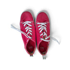A pair of TOMS canvas sneakers in a vibrant magenta pink, featuring white laces and white rubber soles, photographed from a top-down perspective on a white background.