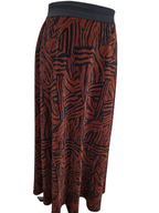 A pleated midi skirt with a rust-orange and black abstract wavy pattern, featuring a solid black waistband.