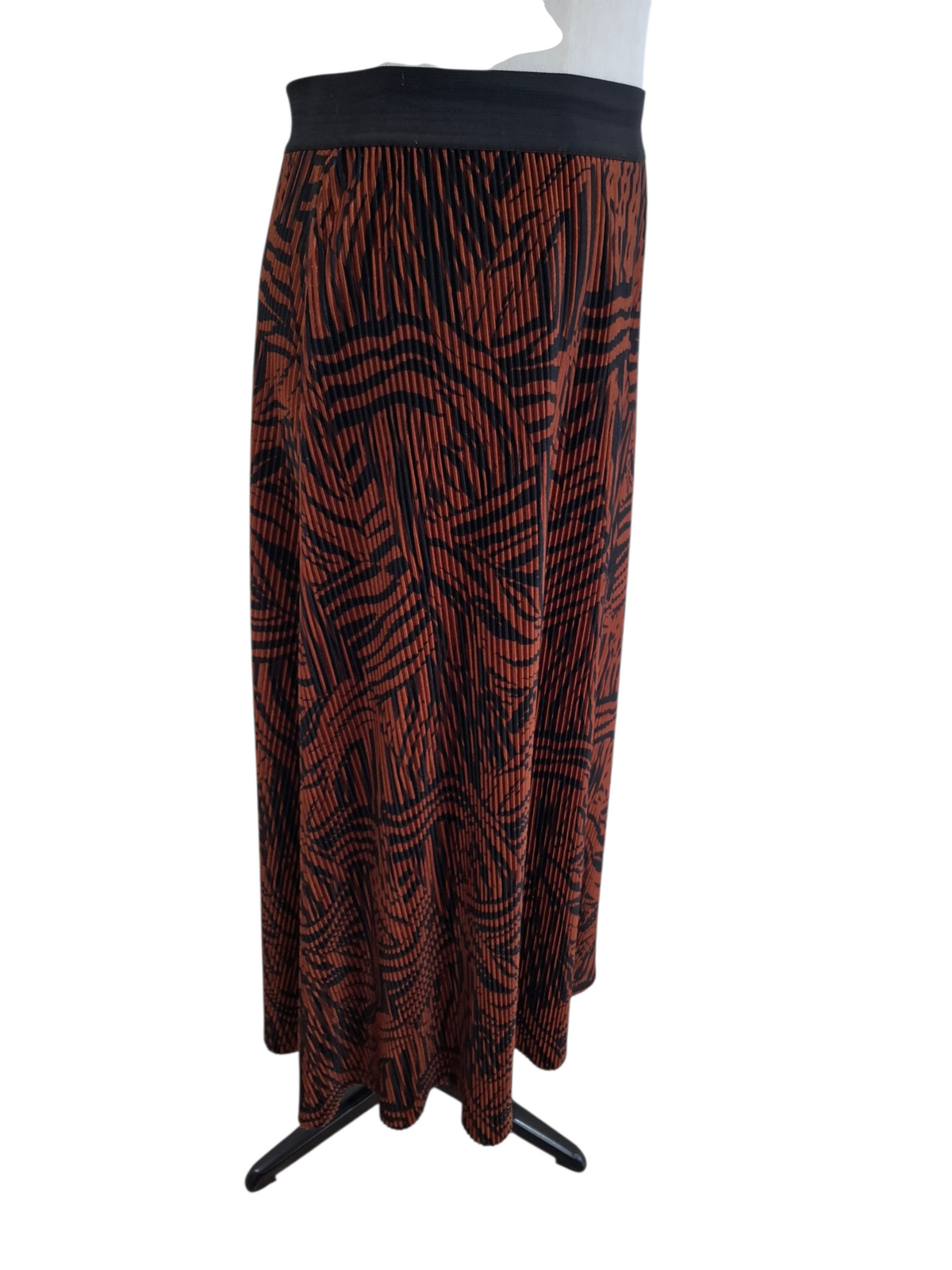 A long pleated skirt with an abstract black and rust-orange pattern, displayed on a white mannequin torso against a white background.