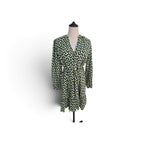 A long-sleeve wrap dress with a green, yellow, and blue geometric pattern, displayed on a mannequin against a white background.