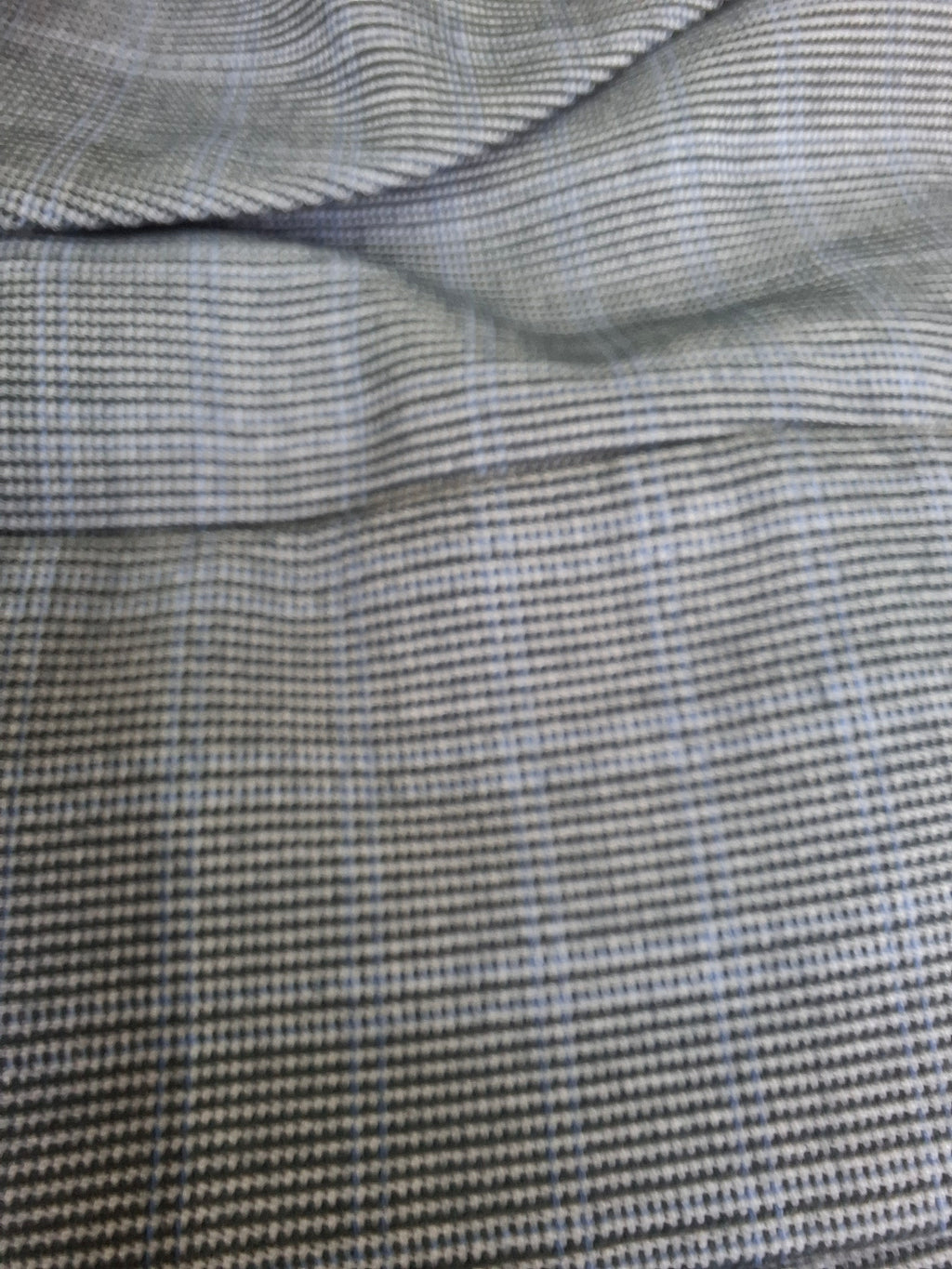 Close-up of a textured fabric with a fine micro-check pattern in gray, black, and light blue.
