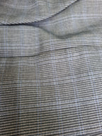 Close-up of a textured fabric with a fine micro-check pattern in gray, black, and light blue.