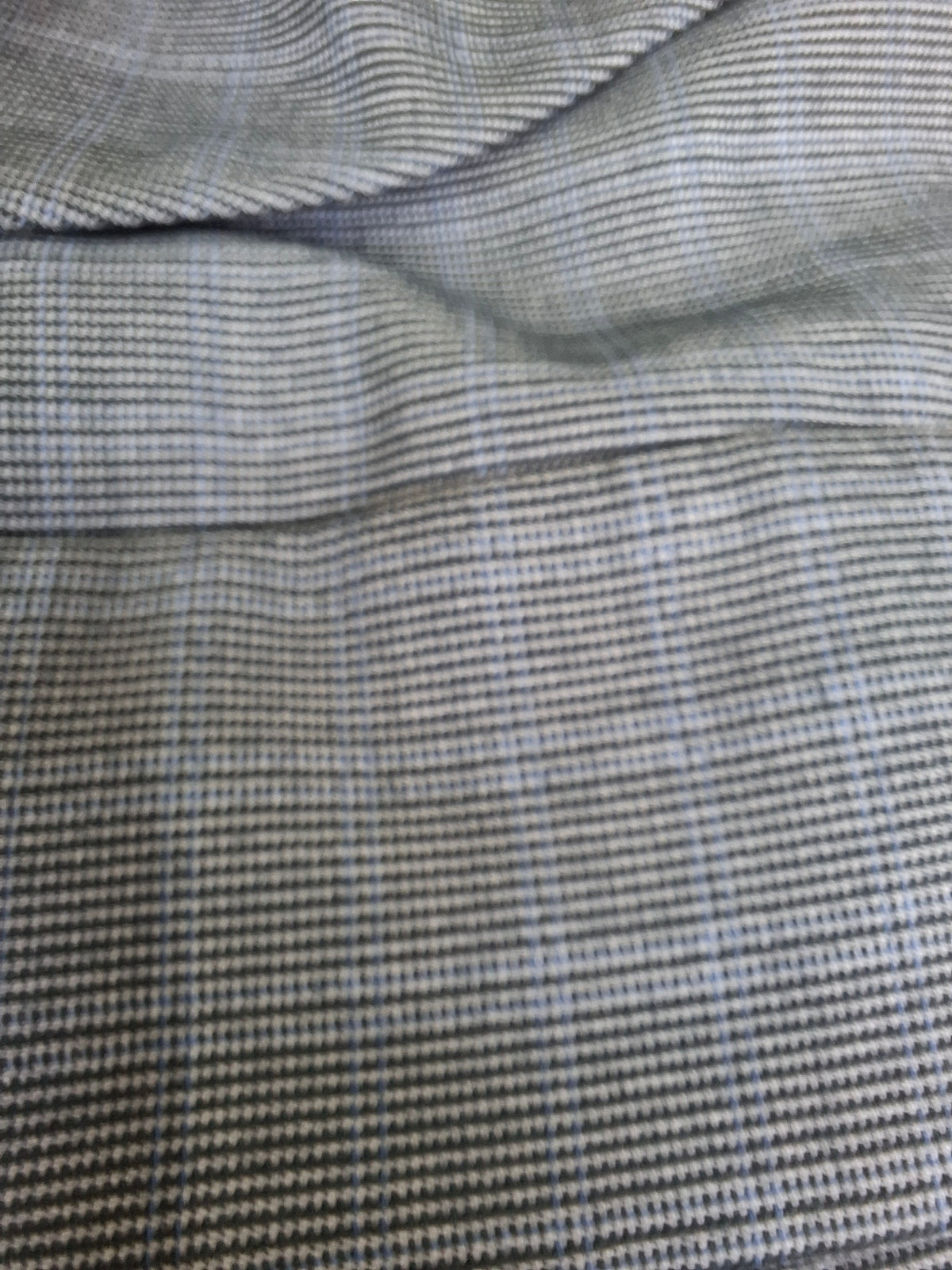 Close-up of a textured fabric with a fine micro-check pattern in gray, black, and light blue.
