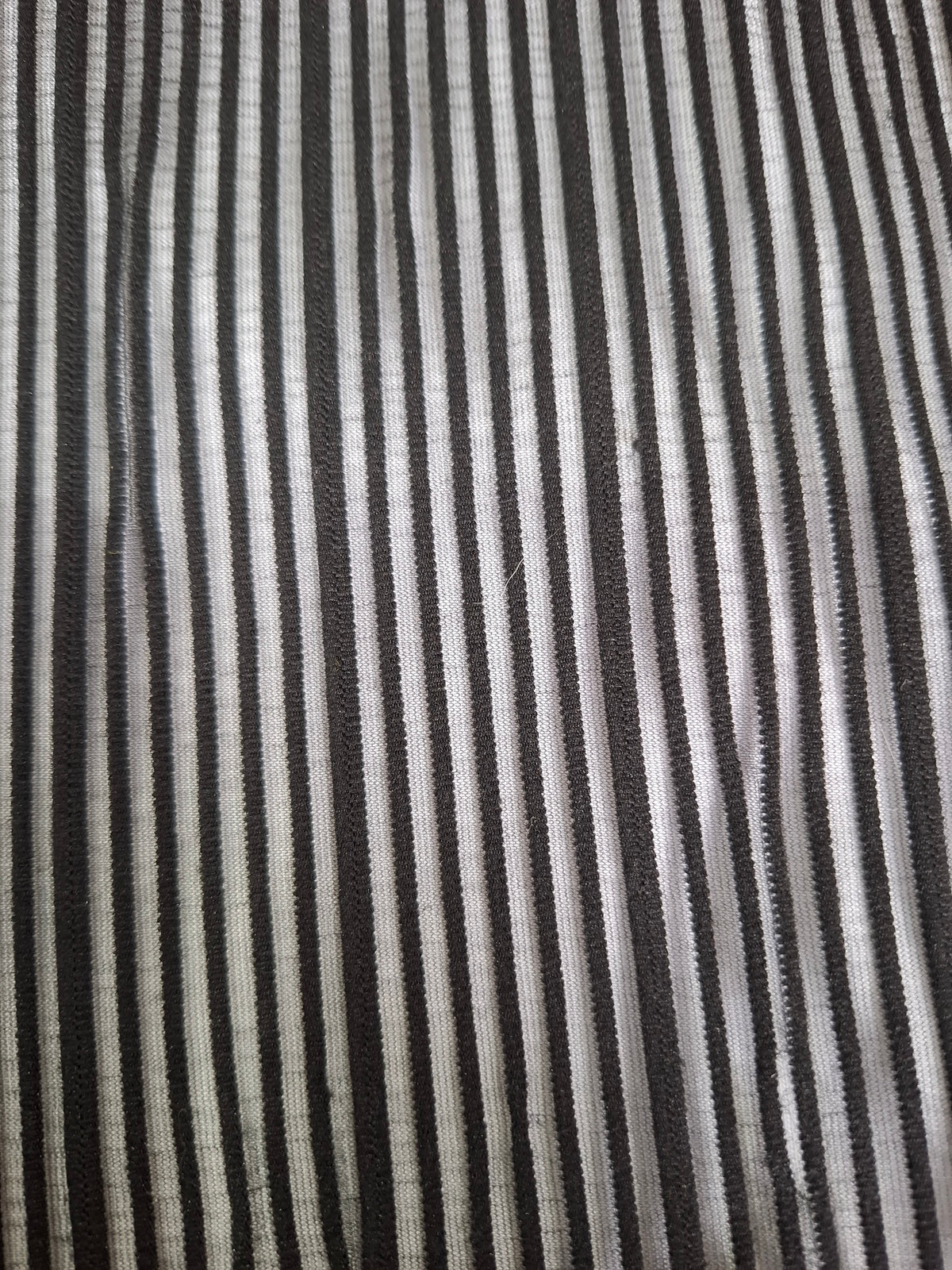 A close-up of a striped fabric with alternating vertical stripes of black, dark gray, and off-white.