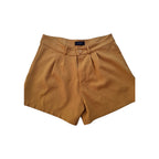 A pair of mustard yellow pleated shorts with a button closure, laid flat on a white background.