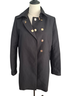 A black double-breasted coat with decorative gold-tone flower-shaped buttons, displayed on a dress form mannequin against a white background.