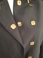 Close-up of a dark charcoal gray double-breasted blazer with prominent round gold-tone metal buttons.