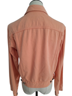A peach-colored denim jacket displayed on a light gray dress form mannequin, showing the back view with button details at the hem.