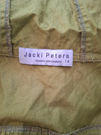 Close-up of a vintage olive green Jacki Peters garment with a white paper brand label sewn onto the inside.