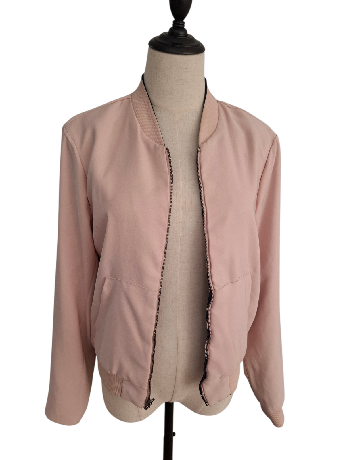 A light pink bomber jacket displayed on a beige dress form mannequin against a plain white background.