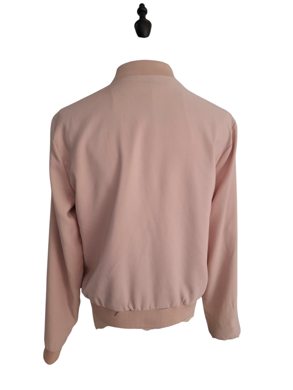 A light pink long-sleeve bomber jacket shown from the back, displayed on a black mannequin torso against a plain white background.
