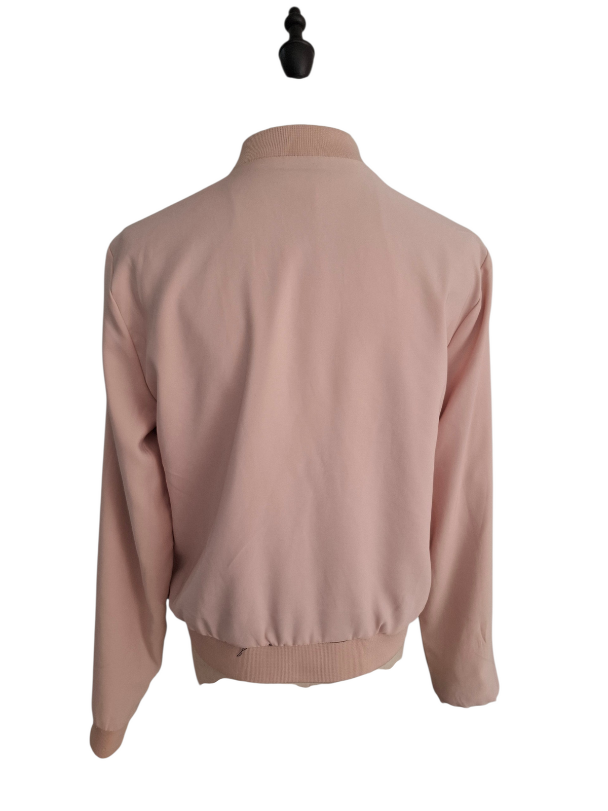 A light pink long-sleeve bomber jacket shown from the back, displayed on a black mannequin torso against a plain white background.
