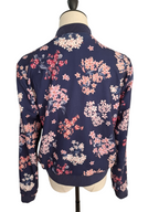 A navy blue bomber jacket with a pink and white floral print, displayed on a mannequin from the back against a white background.