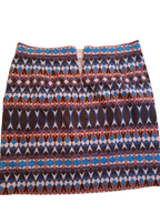 A short A-line skirt with a vibrant geometric ikat pattern featuring blue, purple, brown, and orange on a white background.
