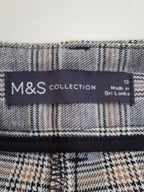 Close-up of a M&S Collection garment label sewn onto a plaid fabric, showing the brand name and 'Made in Sri Lanka' text.