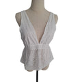 A white sleeveless eyelet lace top with a deep V-neckline, displayed on a beige fabric dress form mannequin against a plain white background.