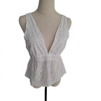 A white sleeveless eyelet lace top with a deep V-neckline, displayed on a beige fabric dress form mannequin against a plain white background.