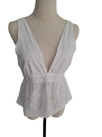 White sleeveless eyelet lace top with a deep V-neckline, displayed on a beige fabric mannequin torso against a plain white background.