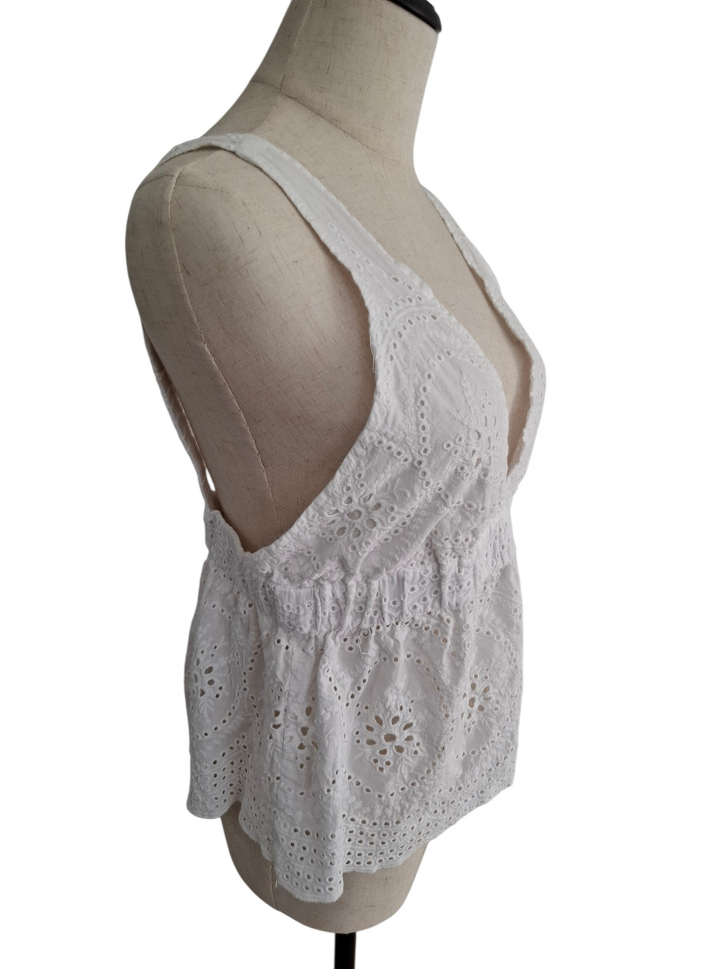 White eyelet lace sleeveless top displayed on a beige dress form mannequin against a white background.