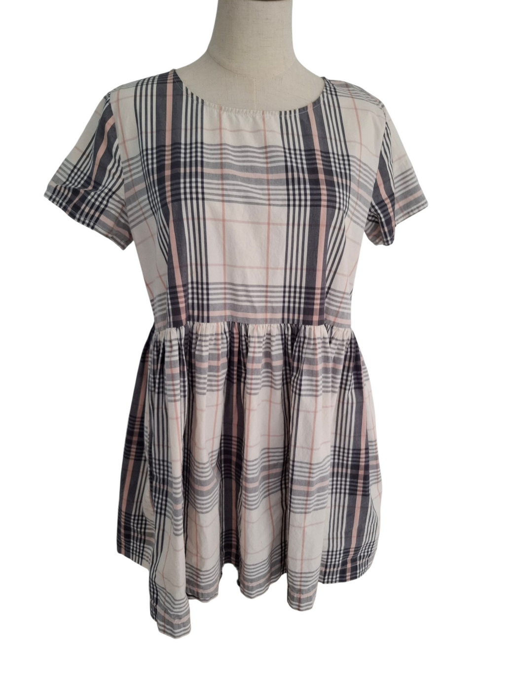 A short-sleeve plaid dress displayed on a mannequin torso against a plain white background. The dress features a beige base with intersecting black, gray, and muted pink plaid lines.