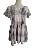 A short-sleeve plaid dress displayed on a mannequin torso against a plain white background. The dress features a beige base with intersecting black, gray, and muted pink plaid lines.