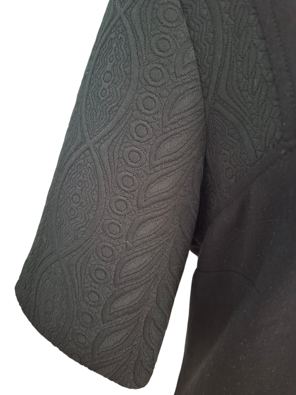 Close-up of a dark gray short-sleeve top showing the textured, patterned sleeve fabric against a white background.