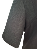 Close-up of a dark gray short-sleeve top showing the textured, patterned sleeve fabric against a white background.