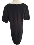 A black short-sleeve dress shown from the back on a mannequin, featuring a central zipper and textured patterned sleeves.