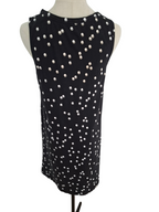 A sleeveless black top with an allover pattern of small white and gold circular embellishments, displayed on a cream-colored dress form against a white background.