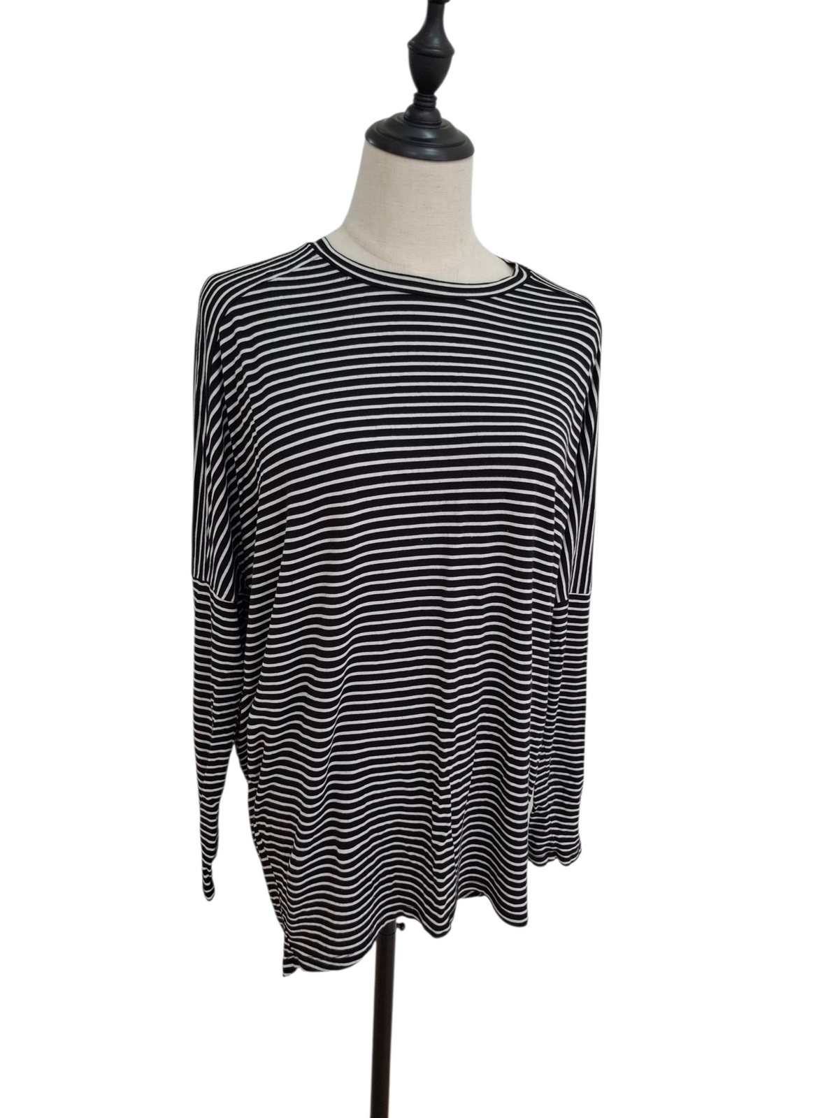 A black and white horizontally striped long-sleeve top displayed on a dress form mannequin against a plain white background.