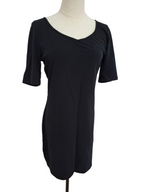 A black short-sleeve shift dress displayed on a cream-colored dress form mannequin against a plain white background.