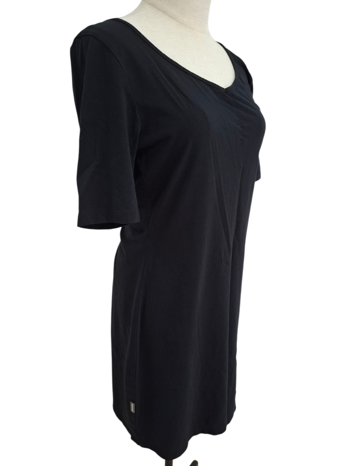 A black short-sleeve tunic top with a draped, gathered neckline, displayed on a cream-colored mannequin torso against a white background.