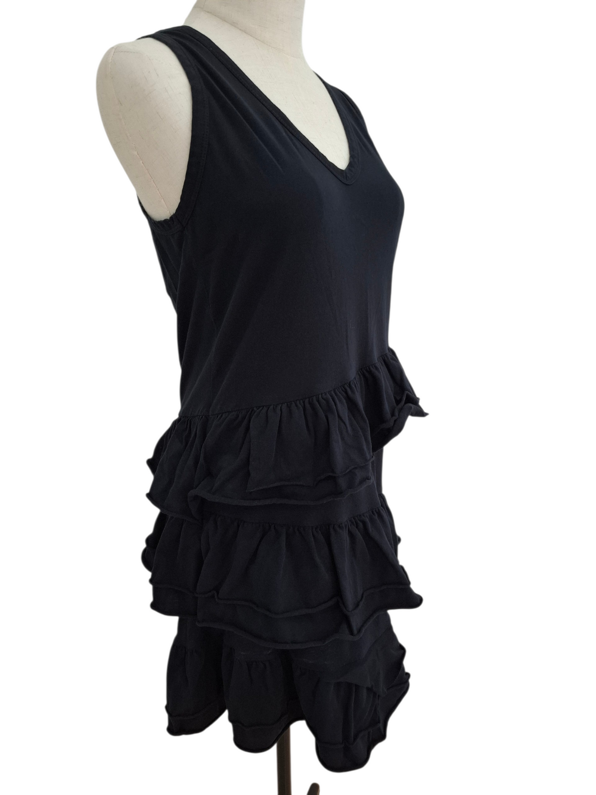 A black sleeveless V-neck top with a tiered ruffle hem, displayed on a cream mannequin torso against a plain white background.