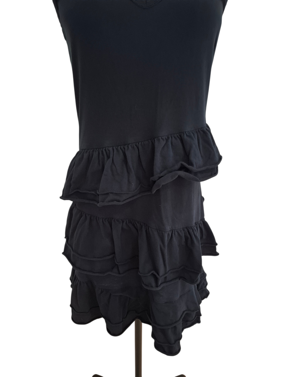 A black sleeveless dress displayed on a dress form mannequin against a plain white background. The dress features a tiered ruffle hem.
