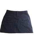 A dark navy blue mini skirt with a button closure and two front flap pockets, laid flat against a white background.