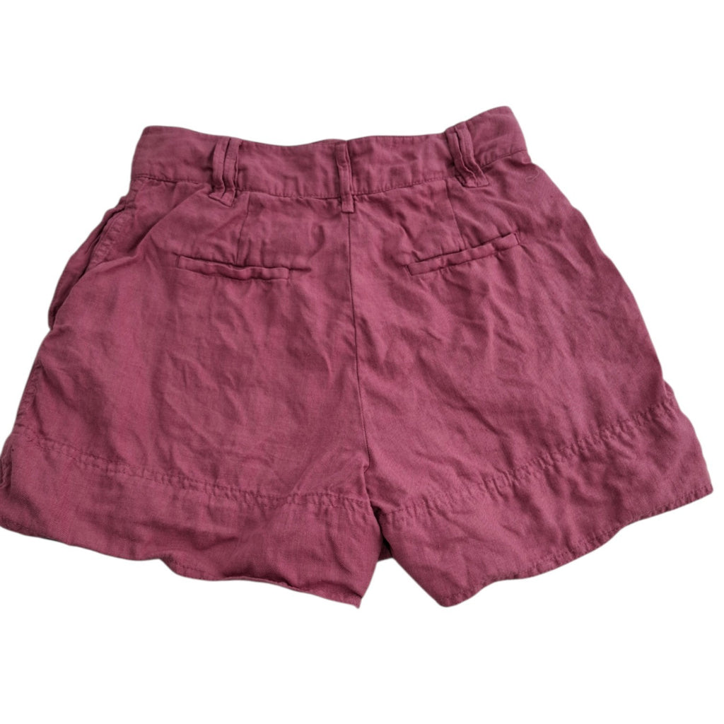 A pair of dusty rose or mauve-colored linen shorts with a relaxed fit, featuring two welt back pockets and a gathered waistband, shown against a plain white background.
