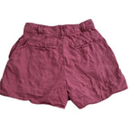 A pair of dusty rose or mauve-colored linen shorts with a relaxed fit, featuring two welt back pockets and a gathered waistband, shown against a plain white background.