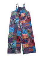 A sleeveless patchwork jumpsuit with a vibrant multicolor print featuring various geometric and paisley patterns in shades of blue, red, pink, orange, and green, shown against a plain white background.