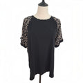 A black short-sleeve top with beige floral lace sleeves, displayed on a mannequin torso against a white background.