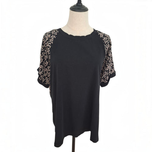 A black short-sleeve top with beige floral lace sleeves, displayed on a mannequin torso against a white background.